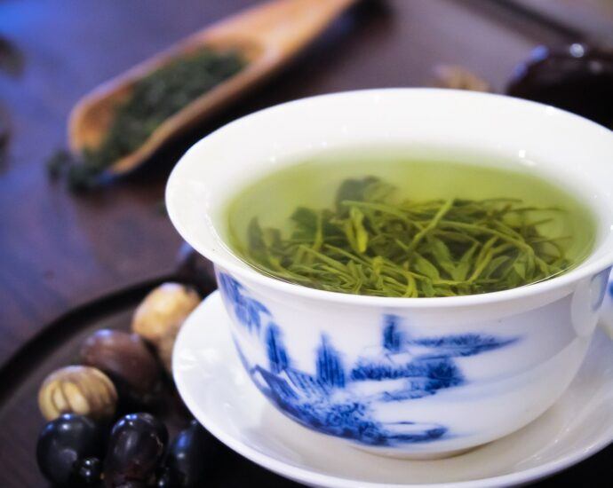 Glass cup of herbal tea on wooden tray table.